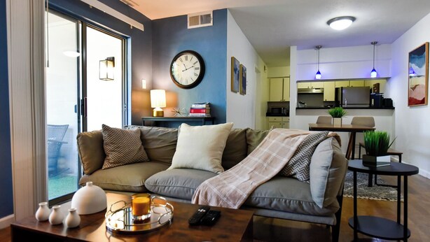 A modern living room with a sofa, coffee table, and a view of the kitchen.