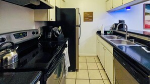 A compact kitchen with a stove, oven, refrigerator, and a coffee maker.