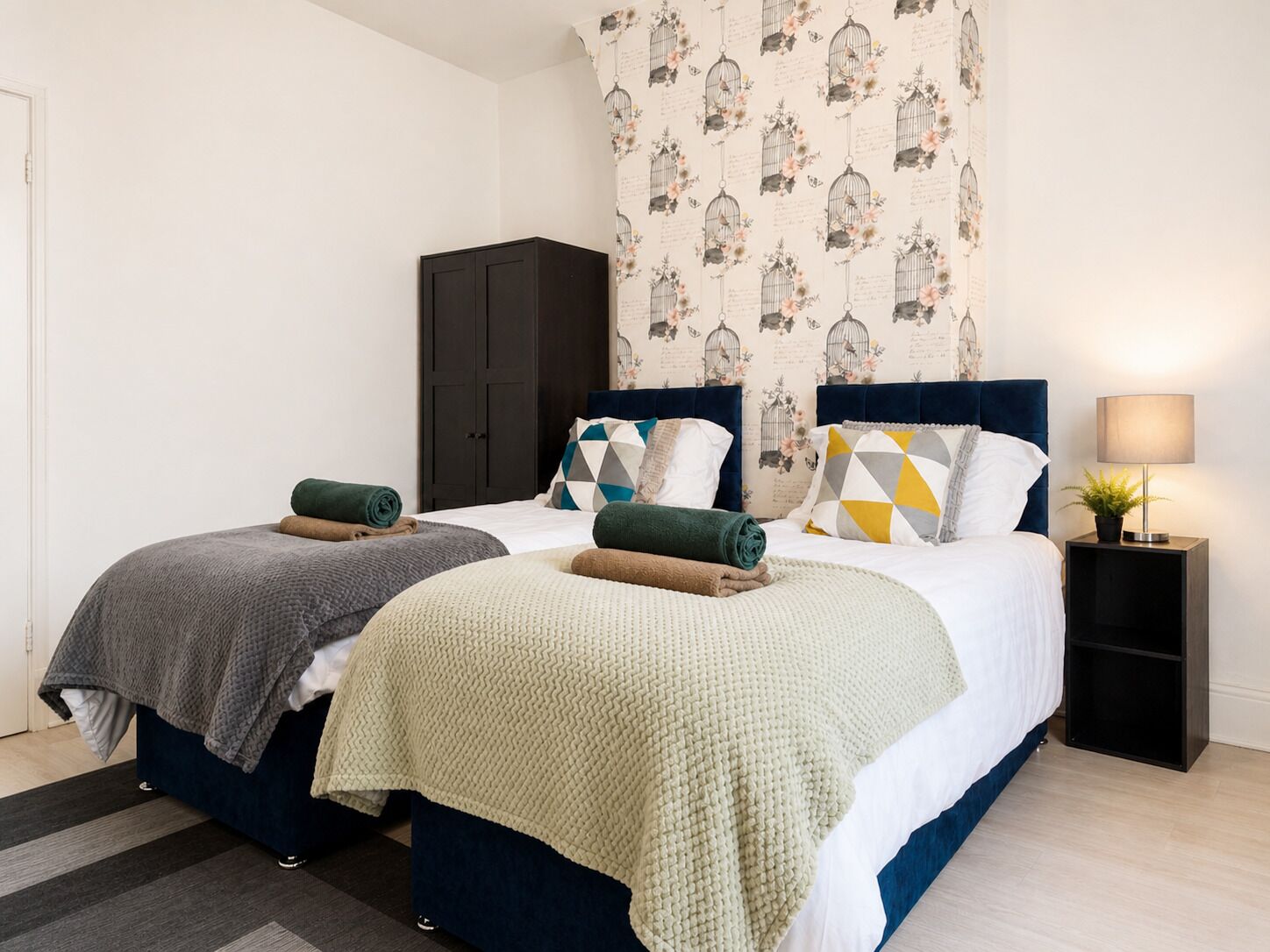 A double bed with a dark headboard, a bedside table with a lamp, and a wardrobe.