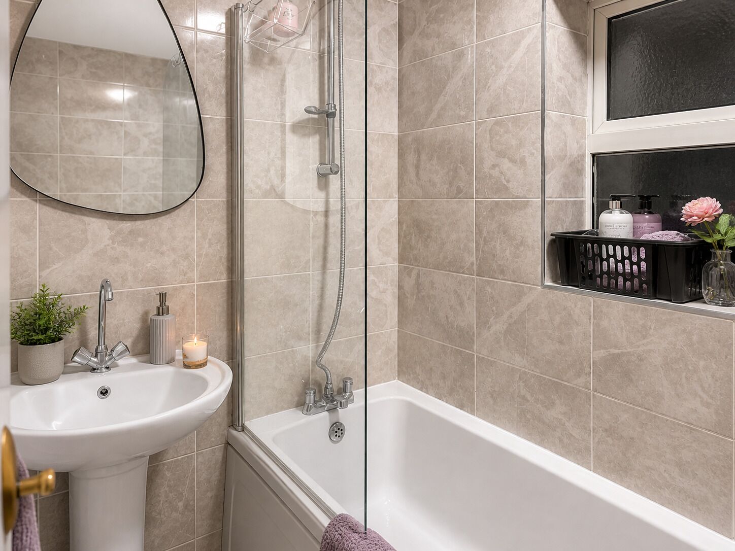 Un baño con lavamanos, espejo, ducha y repisa con artículos de aseo.