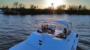 A boat with a covered seating area, a small TV, and a person holding a device.