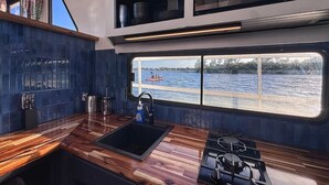 Una cucina con vista sull'acqua, un lavandino, un fornello e una finestra.