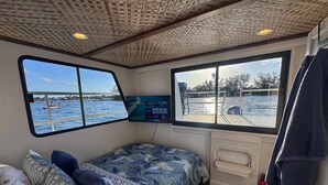 Una cabina con un letto, una finestra vista mare, una TV a muro e un estintore.