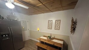 Eine Küche mit Kühlschrank, einer Holzbank und dekorativen Wandverkleidungen.