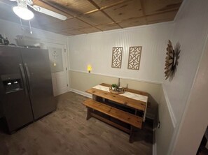 Eine Küche mit Kühlschrank, einer Holzbank und dekorativen Wandverkleidungen.
