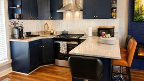 Une cuisine moderne avec des meubles de couleur sombre, un îlot central, une cuisinière et un coin bar.