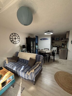 Ein Wohnzimmer mit einer Couch, einem Esstisch und einer Küchenzeile.