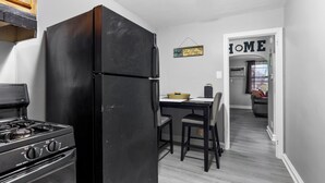 A kitchen with a black refrigerator, a stove, and a dining table with chairs.