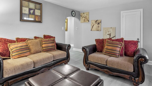 A living room with two leather sofas, a coffee table, and artwork on the walls.