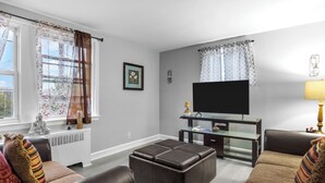 A living room with a flat-screen TV, leather sofas, a glass coffee table, and a fireplace.