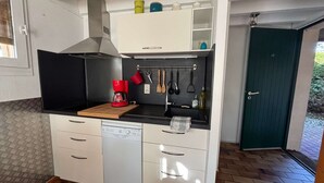 A compact kitchen with a coffee maker, utensils, and storage cabinets. - Vacances proches du lac ! (BISCARROSSE)