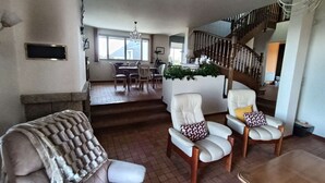 Un salón amplio con escalera, una mesa de comedor con sillas y una chimenea.