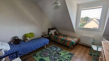 Ein Schlafzimmer mit zwei Betten, einem Fenster, einer Hängelampe und einem Teppich.
