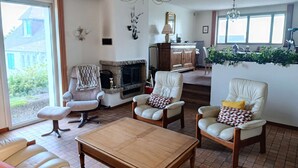 Una sala de estar con chimenea, sillones de cuero, una mesa de centro de madera y un candelabro.