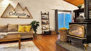 Ein Wohnzimmer mit einer Couch, einem Couchtisch, Holzboden, Kamin und einer Wand mit einem 'Colorado'-Schild.