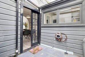 A house entrance with a glass door, a dining area visible through the door, and a copper water pipe on the exterior wall. - A rare fusion of heritage charm and contemporary elegance. Meticulously styled and presented. (Dunedin)