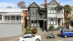 Una casa de estilo victoriano de dos pisos con balcón, cochera y entrada para coches.