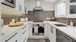 Una cocina moderna con horno empotrado, lavavajillas y un amplio ventanal.