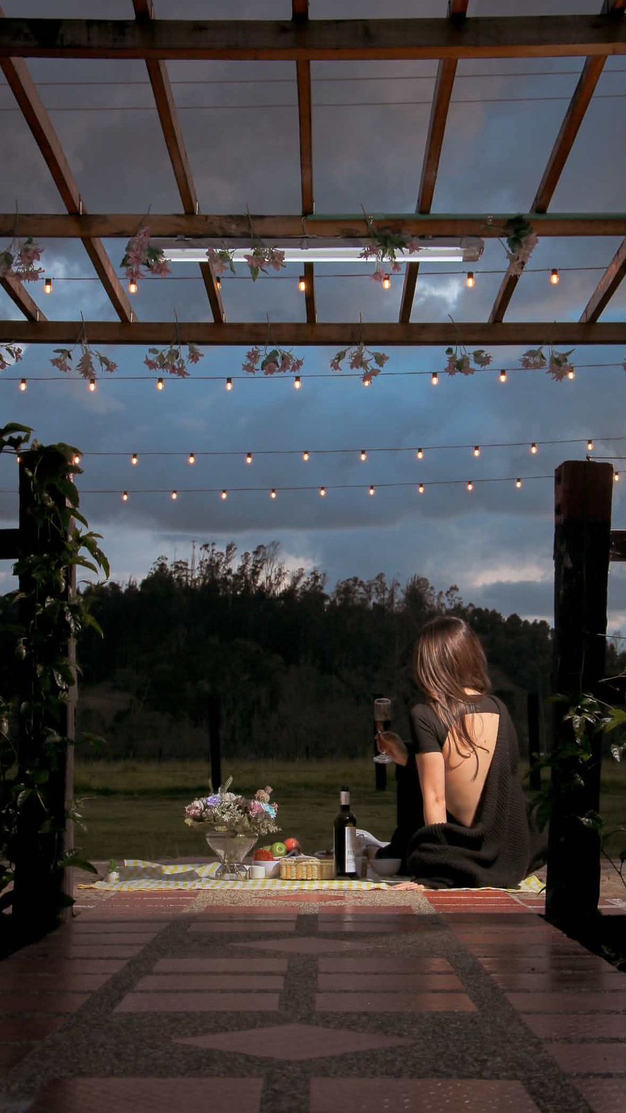 A covered outdoor seating area with string lights and a table set for two.