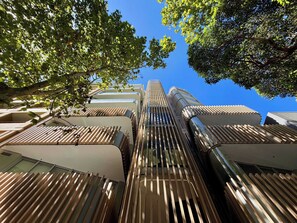 A modern building with a unique sloped roof design, surrounded by trees. - Executive Designer Stay • Central • Gym • Sauna (Surry Hills)