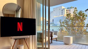 Een moderne woonkamer met een grote flatscreen-tv, een ronde spiegel en een balkon met uitzicht op de stad.