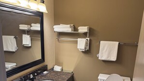 Een badkamer met een dubbele wastafel, toilet en een handdoekrek met opgevouwen handdoeken.