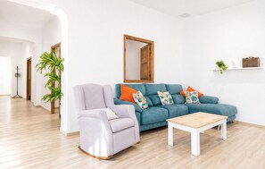 Un salon comprenant un canapé, un fauteuil, une table basse, un miroir et une plante.