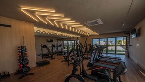 Une salle de sport équipée de tapis de course, de vélos elliptiques et de poids libres.