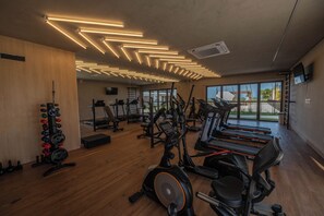 Een fitnessruimte met loopbanden, elliptische trainers en gewichten.