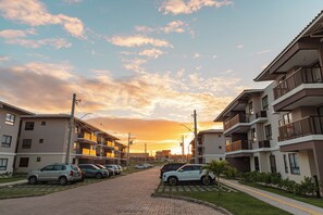 A residential area with multi-story buildings, a paved road, and parked cars. - Beachfront apartment in Ilhéus - Vog Marine - Oceanfront pools - Ideal for families (Ilhéus)