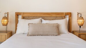 Ein Bett mit Holz-Kopfteil, zwei Nachttischlampen und zwei Kissen.