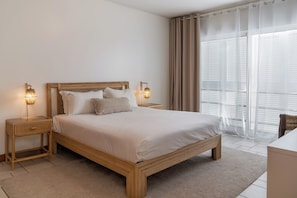 A bedroom with a wooden bed, two bedside tables, a nightstand, a desk, and a window with curtains. - Casa da Moagem – Modern and Relaxing Stay (Barroca)