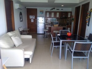 A living room with a sofa, dining table, chairs, a kitchen in the background, and a refrigerator. - Ven y disfruta de tus mejores vacaciones frente al mar, (Cartagena de Indias)
