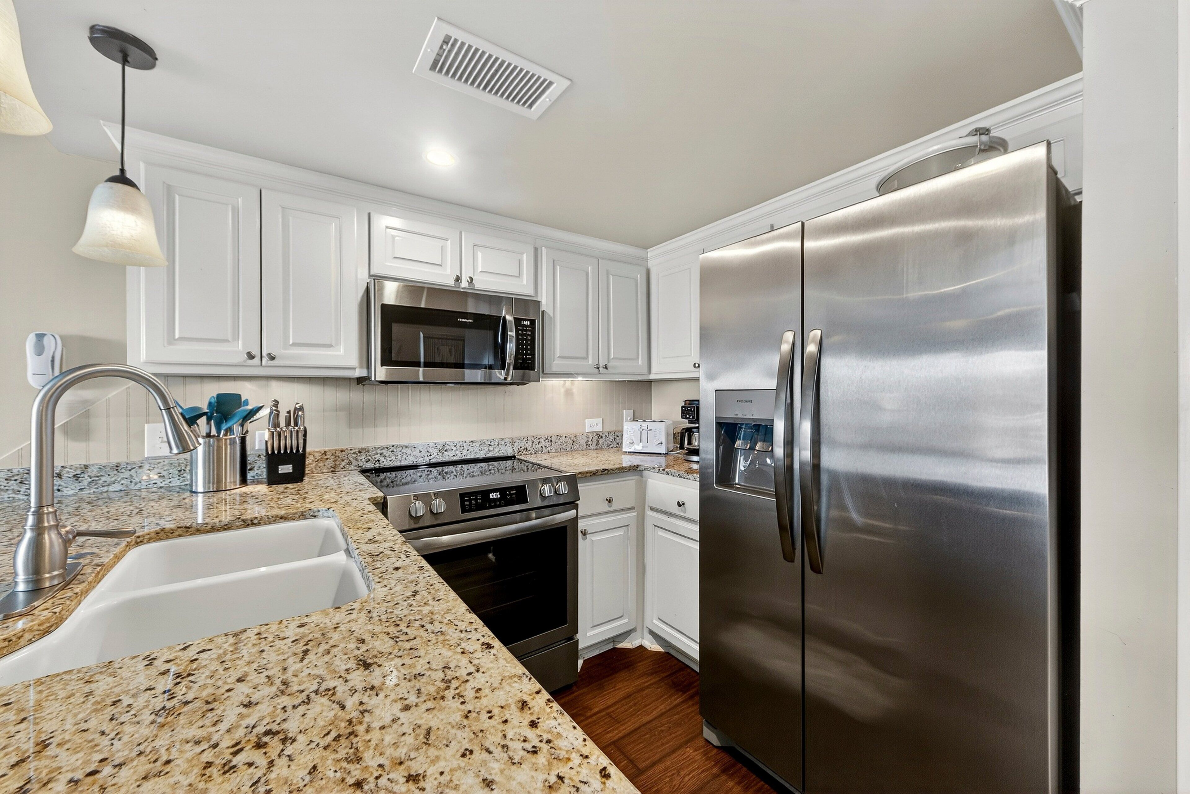 A kitchen with white cabinets, stainless steel appliances, granite countertops, and a built-in oven.