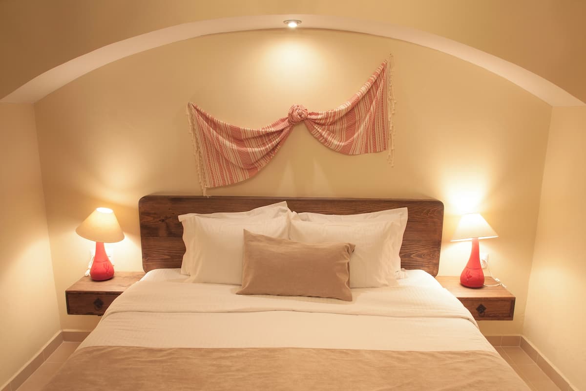 A neatly made bed with a wooden headboard, two bedside tables with lamps, and a decorative bow on the wall.