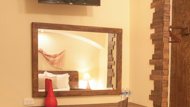 A bathroom with a wooden vanity, a mirror, a television mounted above, and a shower area with a wooden partition. - Hotel Del Parque (Huamantla)