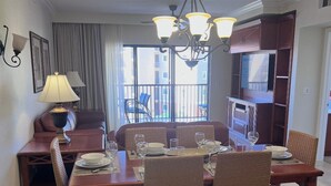 Un coin repas avec une table dressée pour quatre personnes, un lustre et une vue sur l’extérieur.