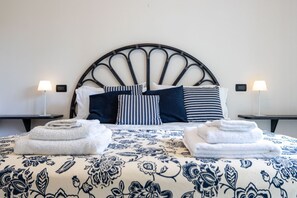 Una cama con cabecera, almohadas y toallas dobladas.