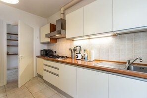 A modern kitchen with white cabinets, a wooden countertop, a gas stove, a sink, and a built-in oven.