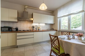 Una cocina moderna con armarios blancos, estufa a gas, microondas y un comedor con mesa y sillas.