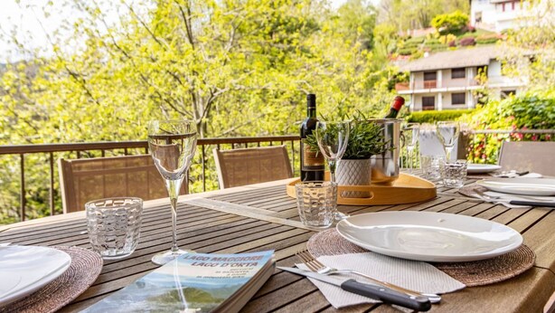A dining table set outdoors with wine glasses, a book, and a menu.