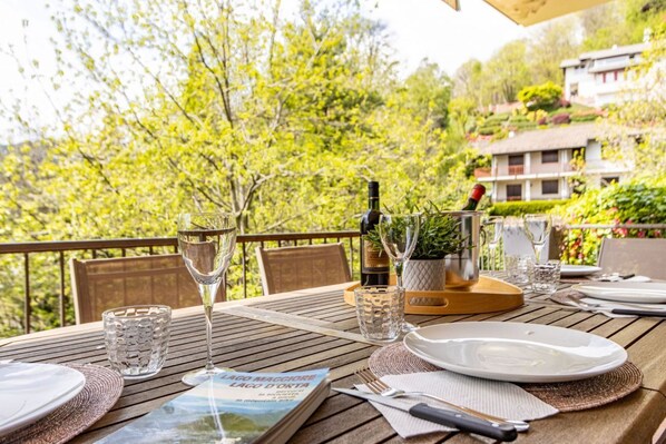 Mesa de comedor al aire libre con copas de vino, un libro y una carta.