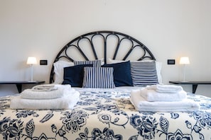 A bed with a headboard, pillows, and folded towels.