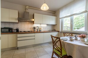 A modern kitchen with white cabinets, a gas stove, a microwave, and a dining area with a table and chairs.