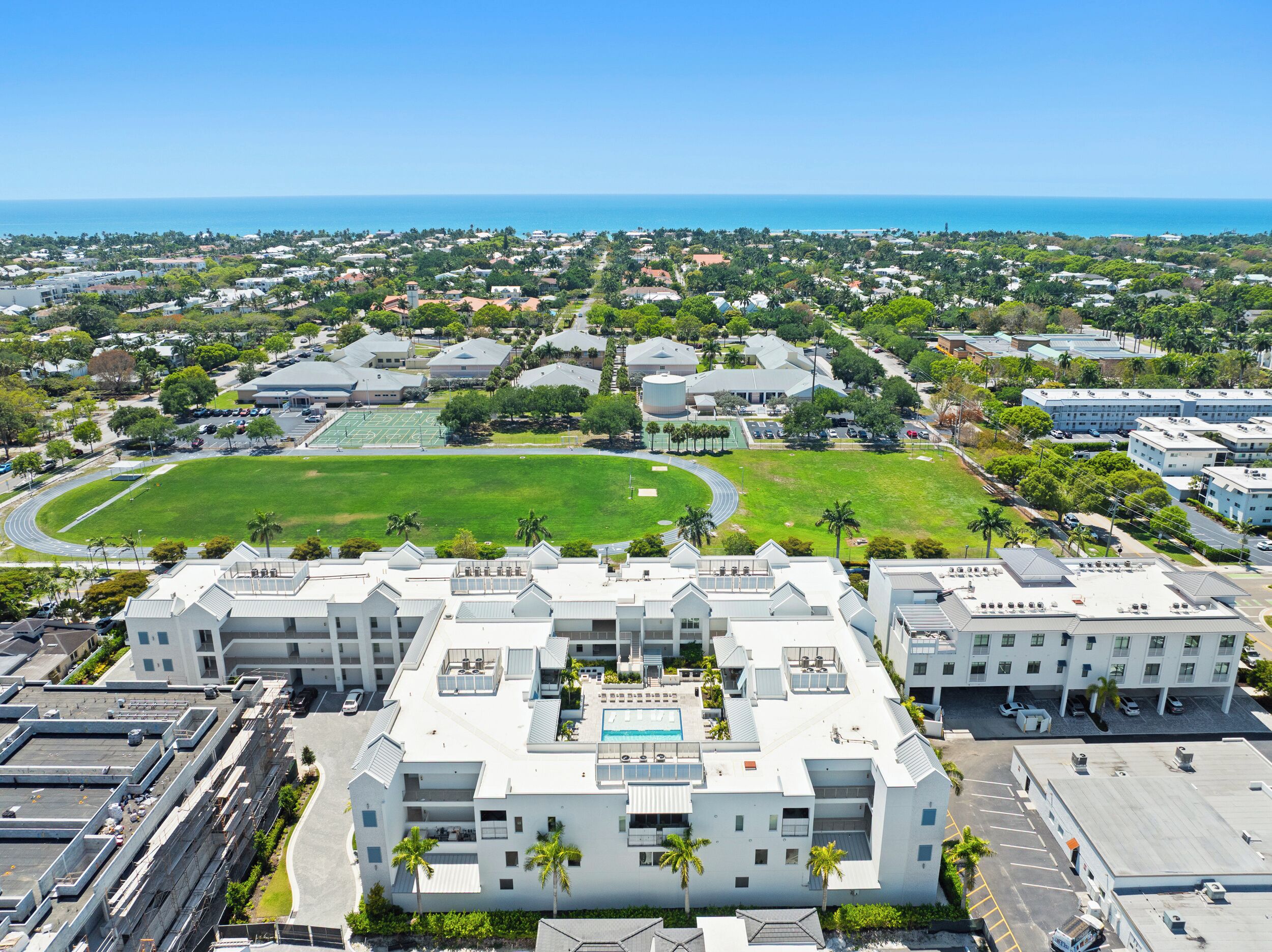 A modern hotel with a rooftop pool, a tennis court, and a view of the ocean.