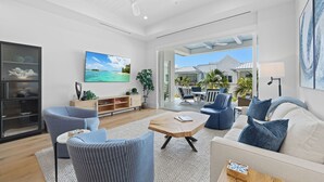 A spacious living room with a large TV, comfortable seating, and a view to the outside. - 🌴 Olde Naples Luxury at The Mark | Walk to Beach + 5th Ave | Weekly Stays | Resort Pool & Spa (Naples)