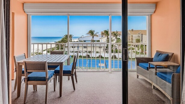 Ein Balkon mit Blick auf den Strand, einen Pool und Gebäude im Hintergrund.
