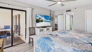 Ein Hotelzimmer mit einem Bett, einem Fernseher, einem Deckenventilator und einer Glasschiebetür, die auf einen Balkon führt.