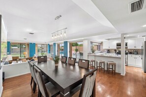 A spacious kitchen with white cabinets, a dining area with a large wooden table, and a view of the outdoors. - Desert Valley Retreat 3BD - Pool + Putting Green (Phoenix)