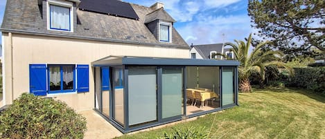 A modern house with a glass conservatory, a sloped roof, and a well-maintained lawn.